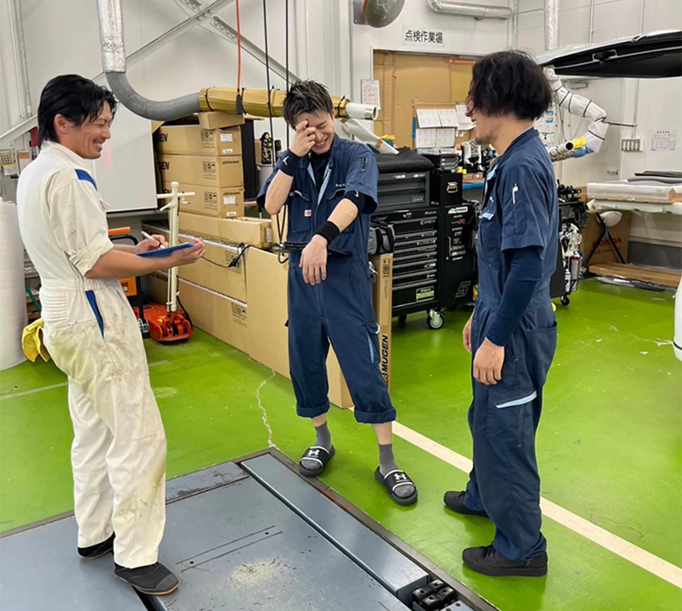 整備工場で楽しく雑談する３人の整備士